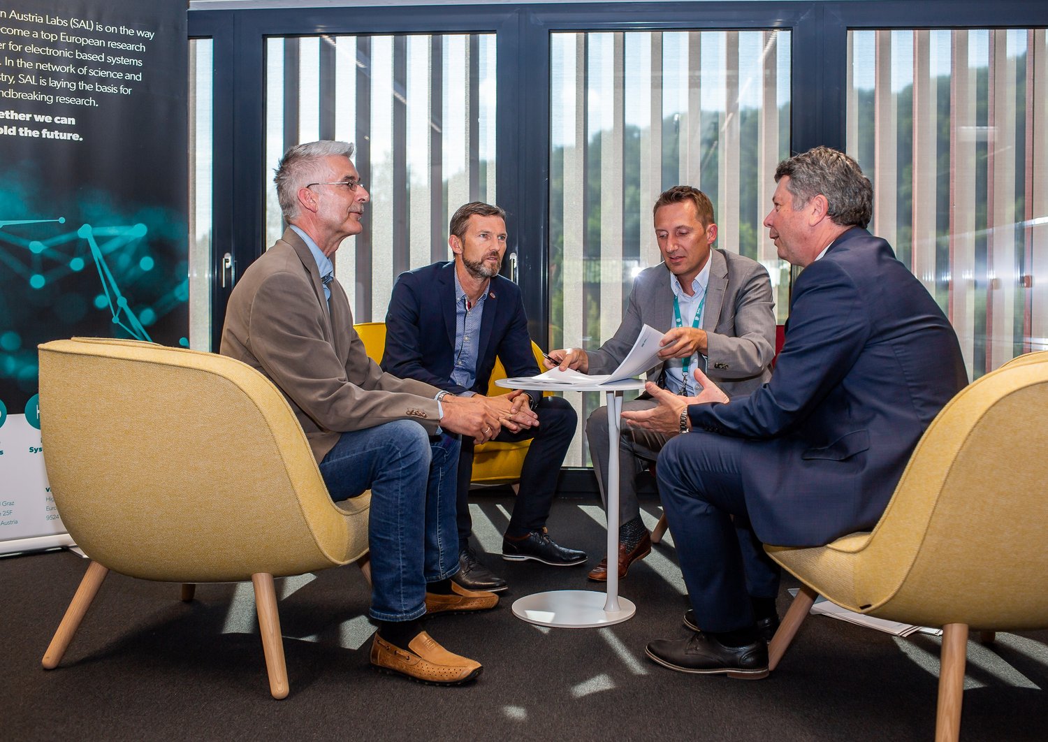Vier Männer sitzen an einem Tisch und sprechen