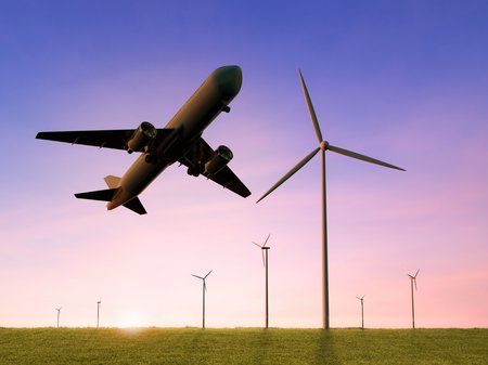 A plane taking off and in the background is a wind turbine