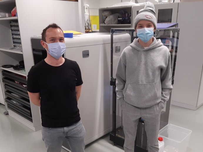 Ein Forscher und ein Jugendlicher stehen zusammen in einem Labor