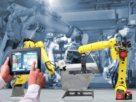 Roboter in einer Fabrik werden von Mensch über Tablet gesteuert