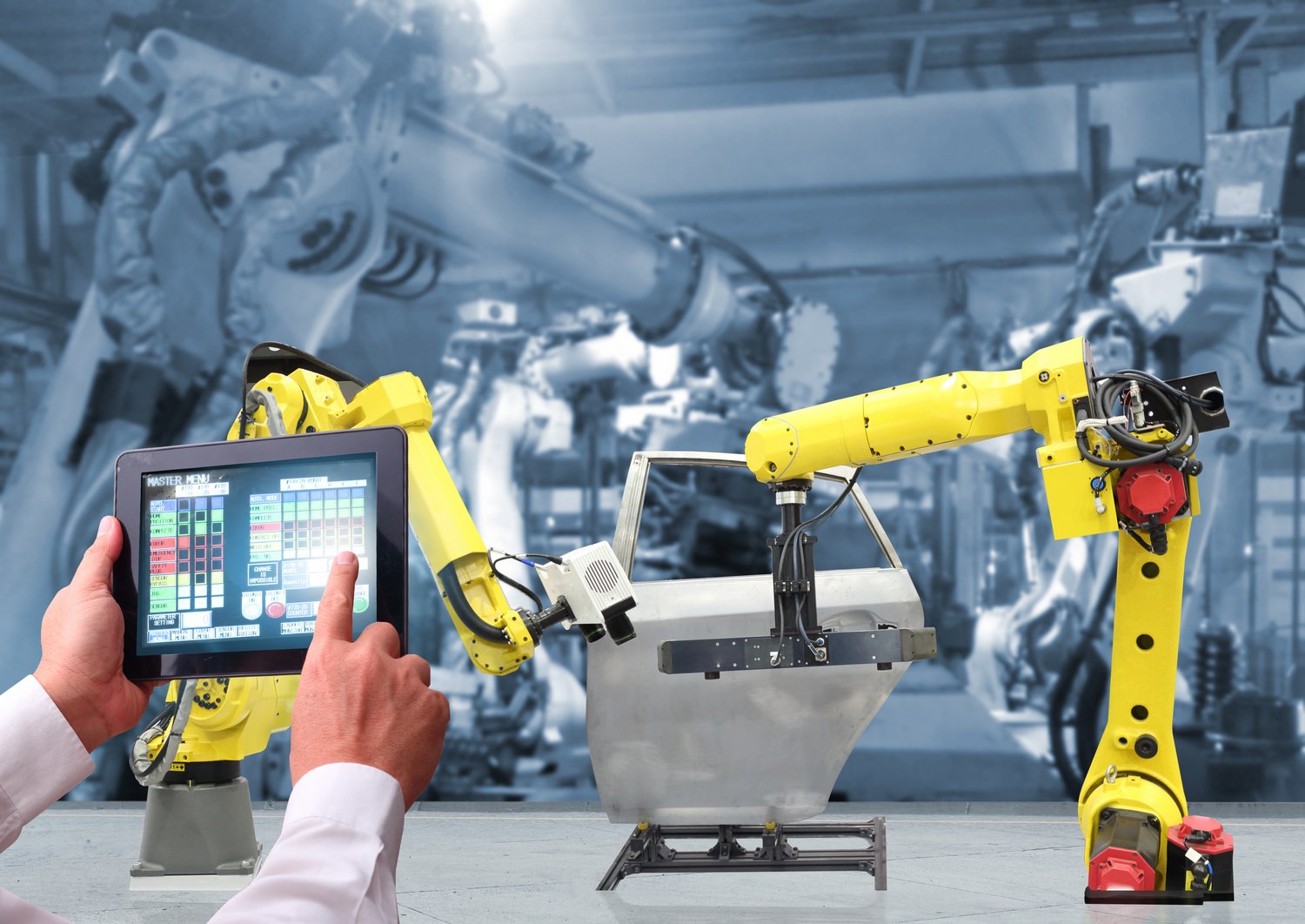 robots in a factory are being controlled by a person with a tablet