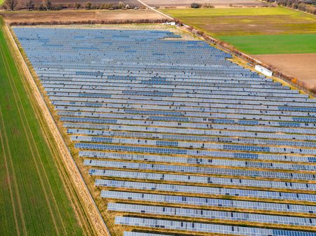 In the middle are slightly damaged PV systems. Surrounding the PV Systems there are yellow and green fields.