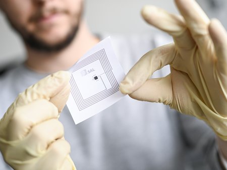 A scientist is holding a printed sensor up close