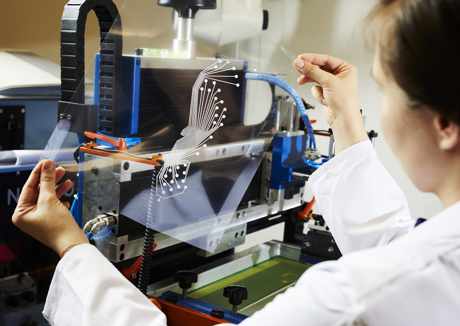 Tutku is inspecting a printed, see-through sensor sheet in the form of a shoe sole. 