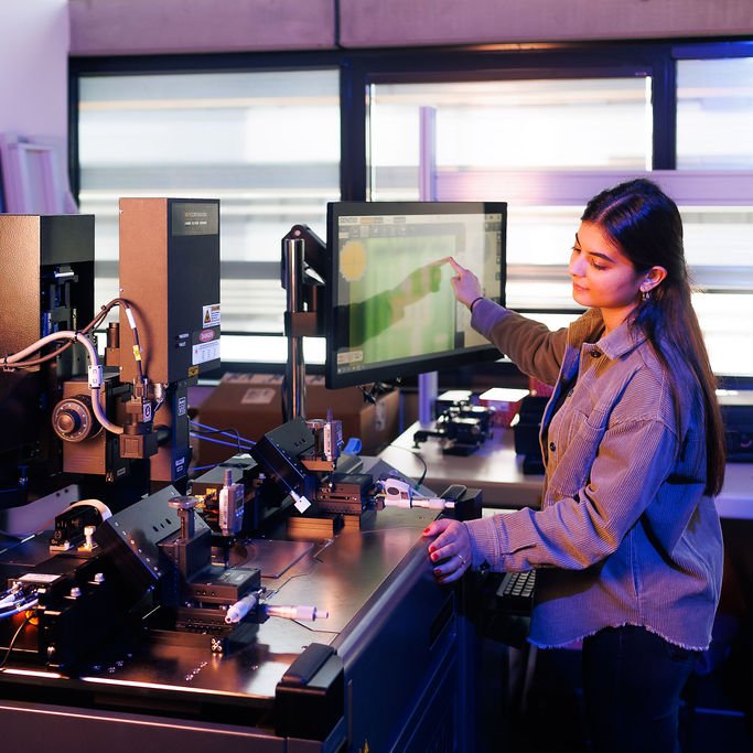 Frau zeigt auf einen Computerbildschirm im Labor