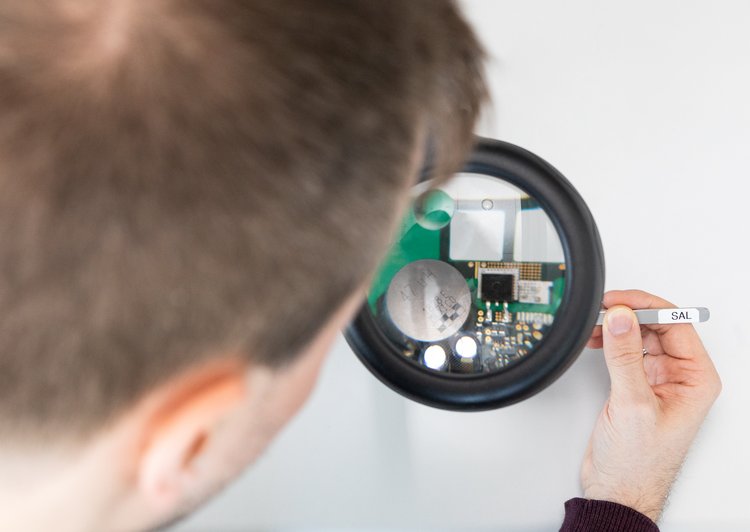 Man looks at circuit board through a microscope