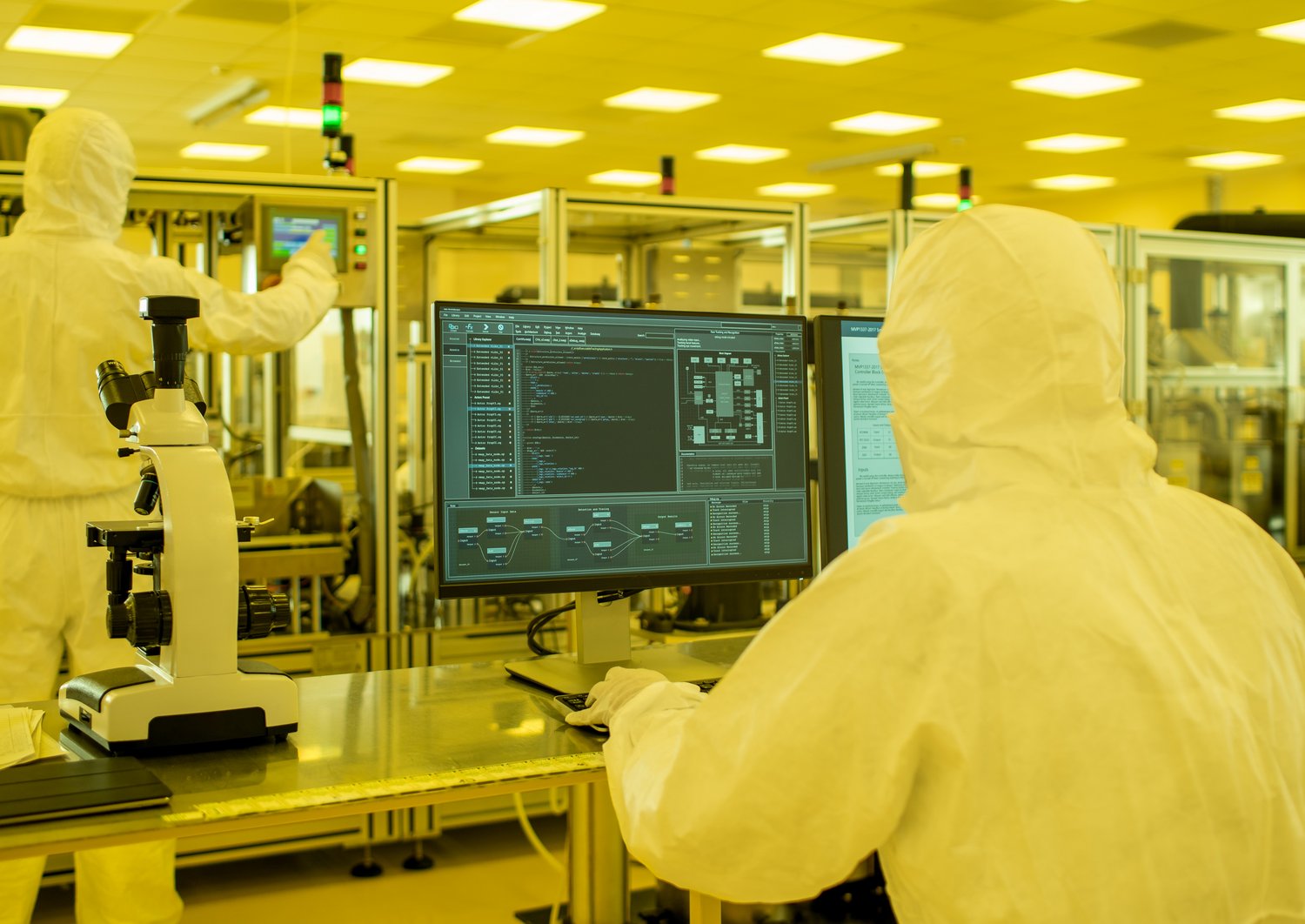 Researchers in sterile suits work with computers in a cleanroom