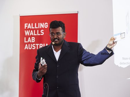 Mani in a suit, presenting at the Falling Walls Lab.