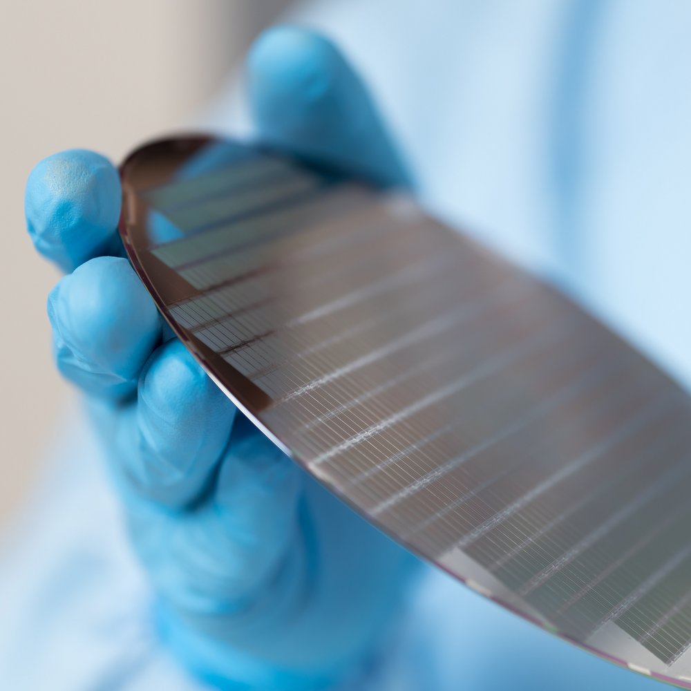 close-up of gloved hands which hold a wafer