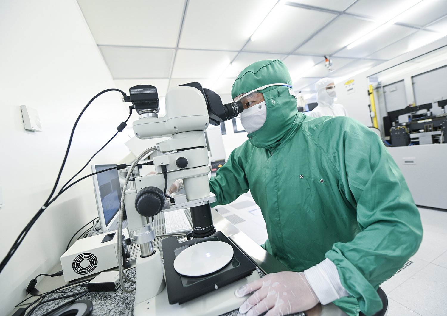 A researcher looking through a microscope in the clean room