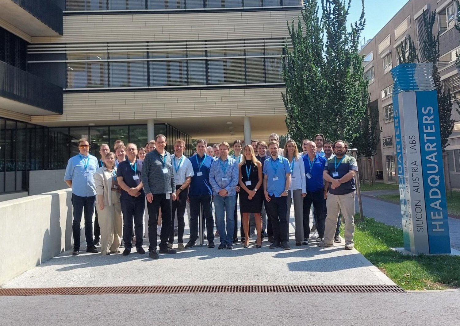 Group of approximately 30 people standing in front of the SAL building in Graz. To their right you can see a pillar that says "Silicon Austria Labs". 