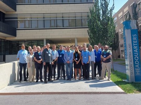 Group of approximately 30 people standing in front of the SAL building in Graz. To their right you can see a pillar that says "Silicon Austria Labs". 
