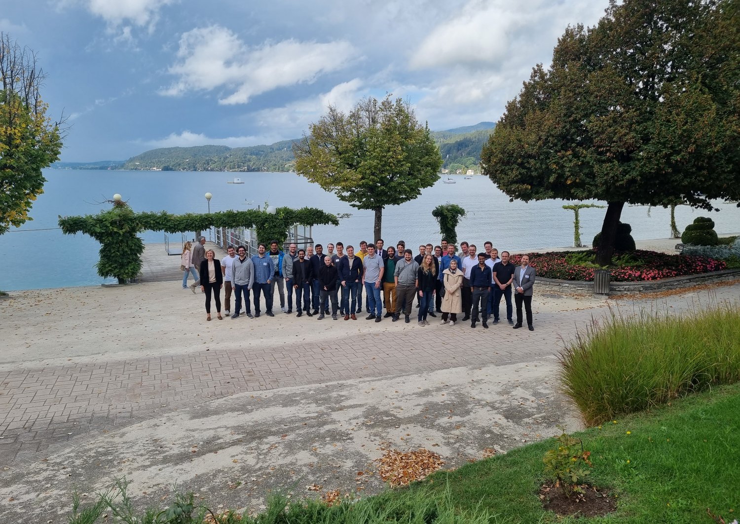 group picture of about 30 people in front of lake Wörthersee on a sunny day