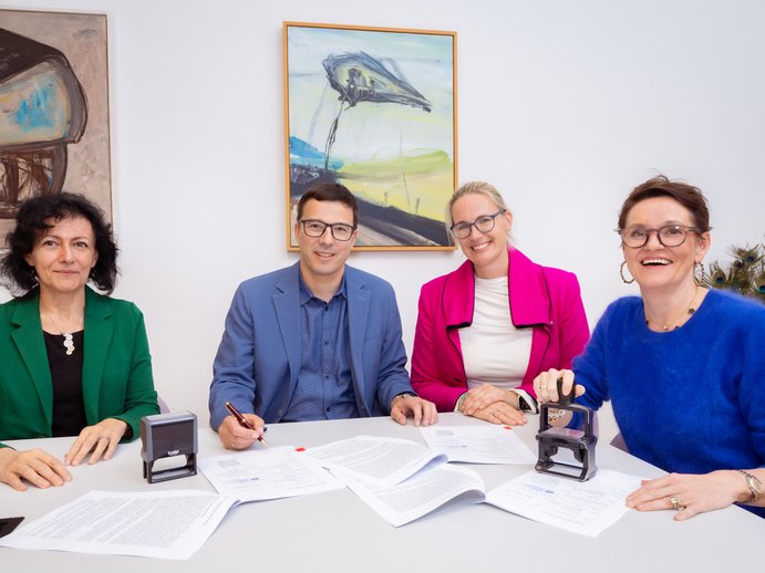 4 people sitting at a table, signed contract in front of them