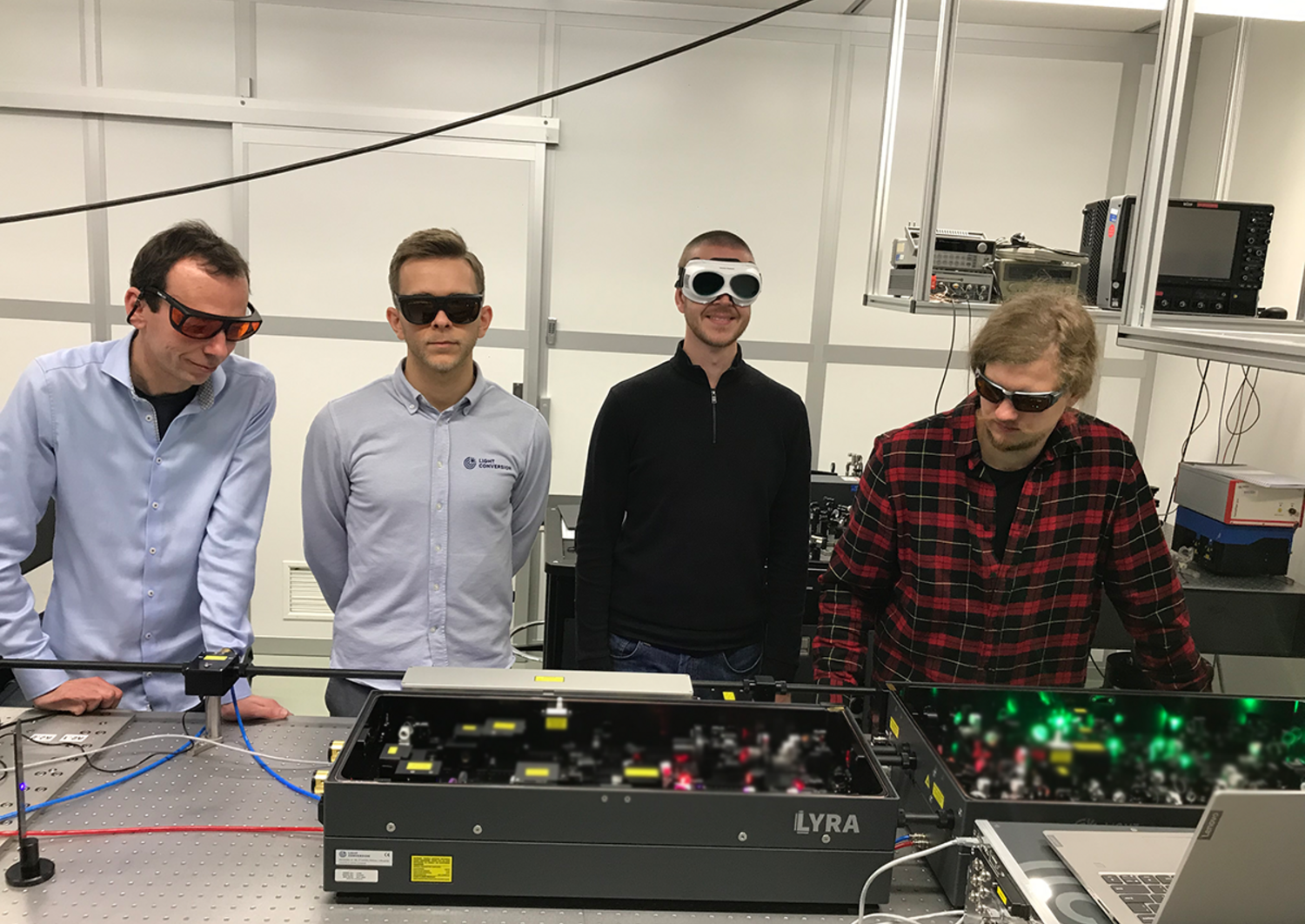 four researchers at the FS Laser System in a lab