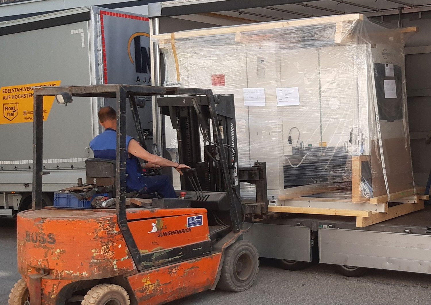 climate chamber being unloaded from a truck with a forklift