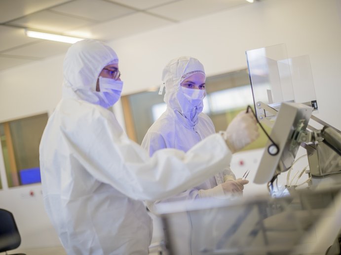 Two scientists working on something in cleanroom clothing in a cleanroom 