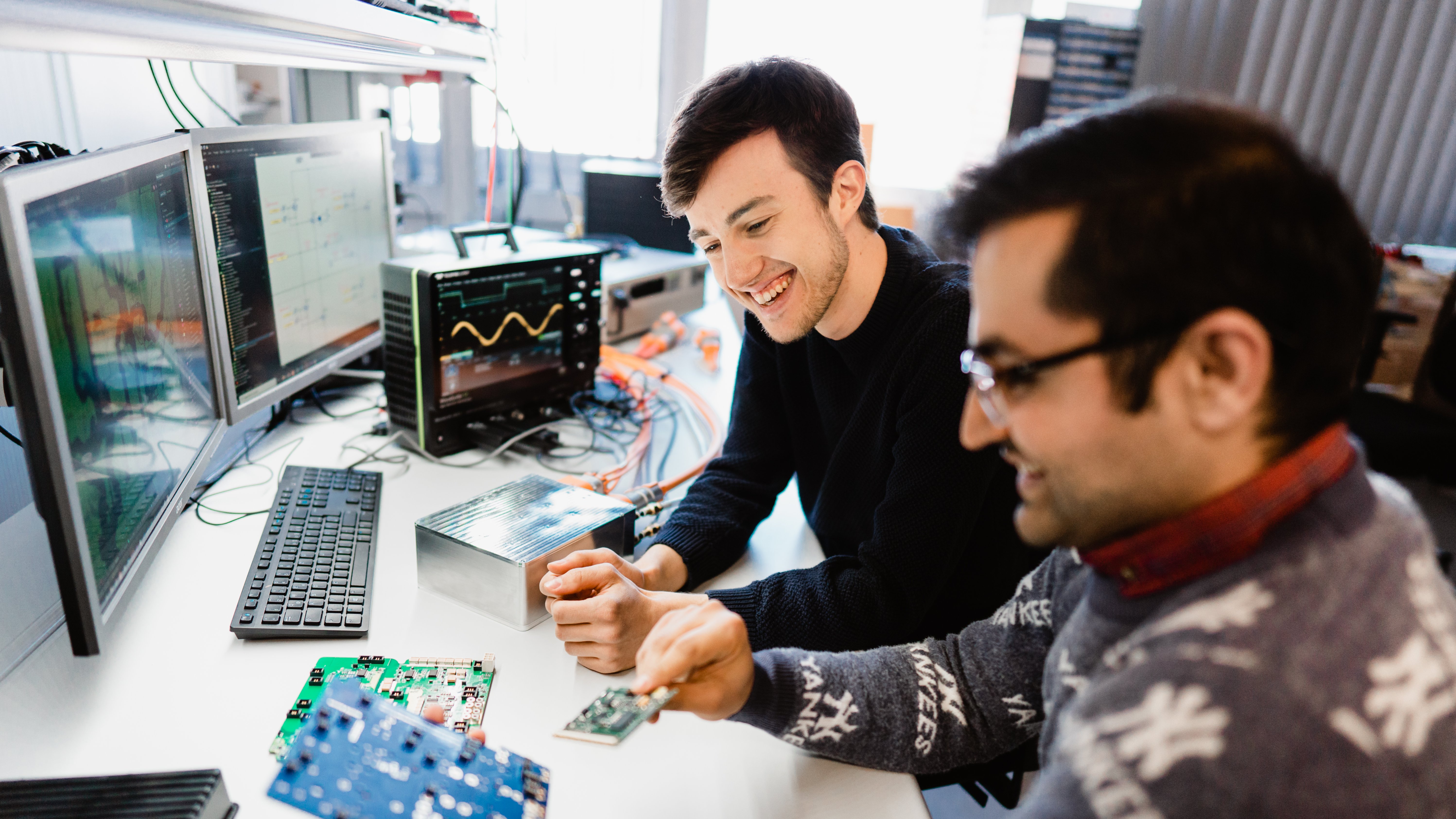 two researchers looking at a printed circuit board