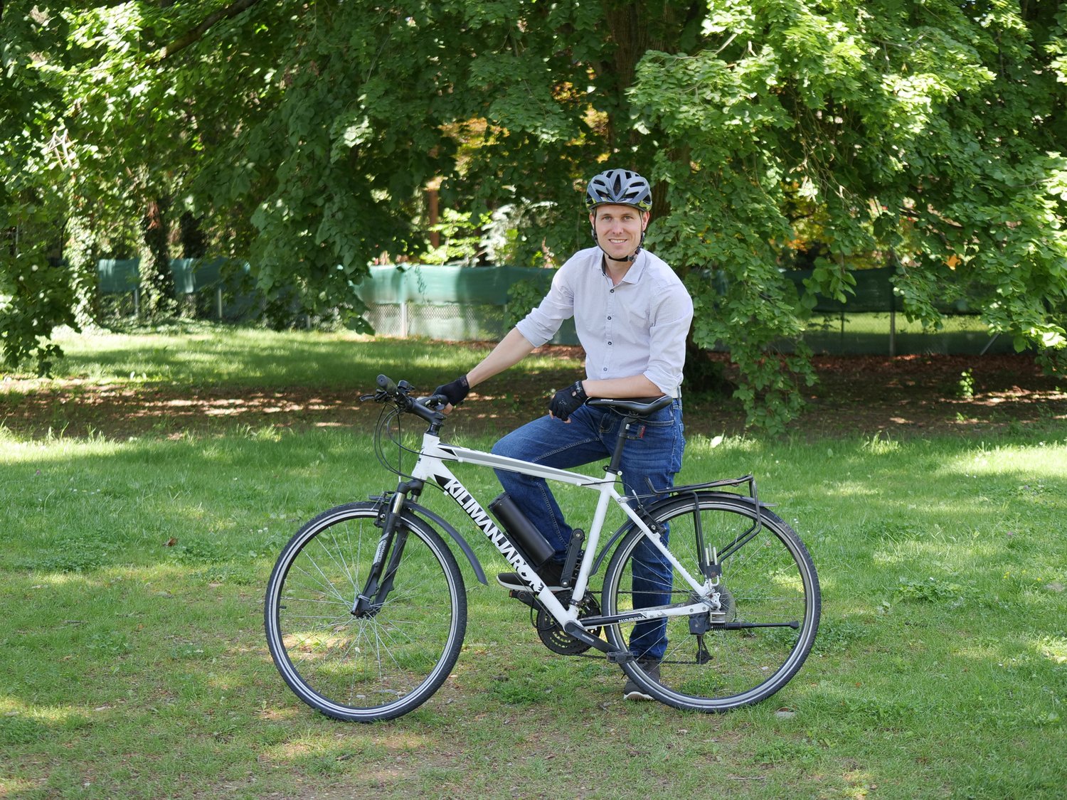 Ein Mann der mit seinem Fahrrad auf einer grünen Wiese steht 