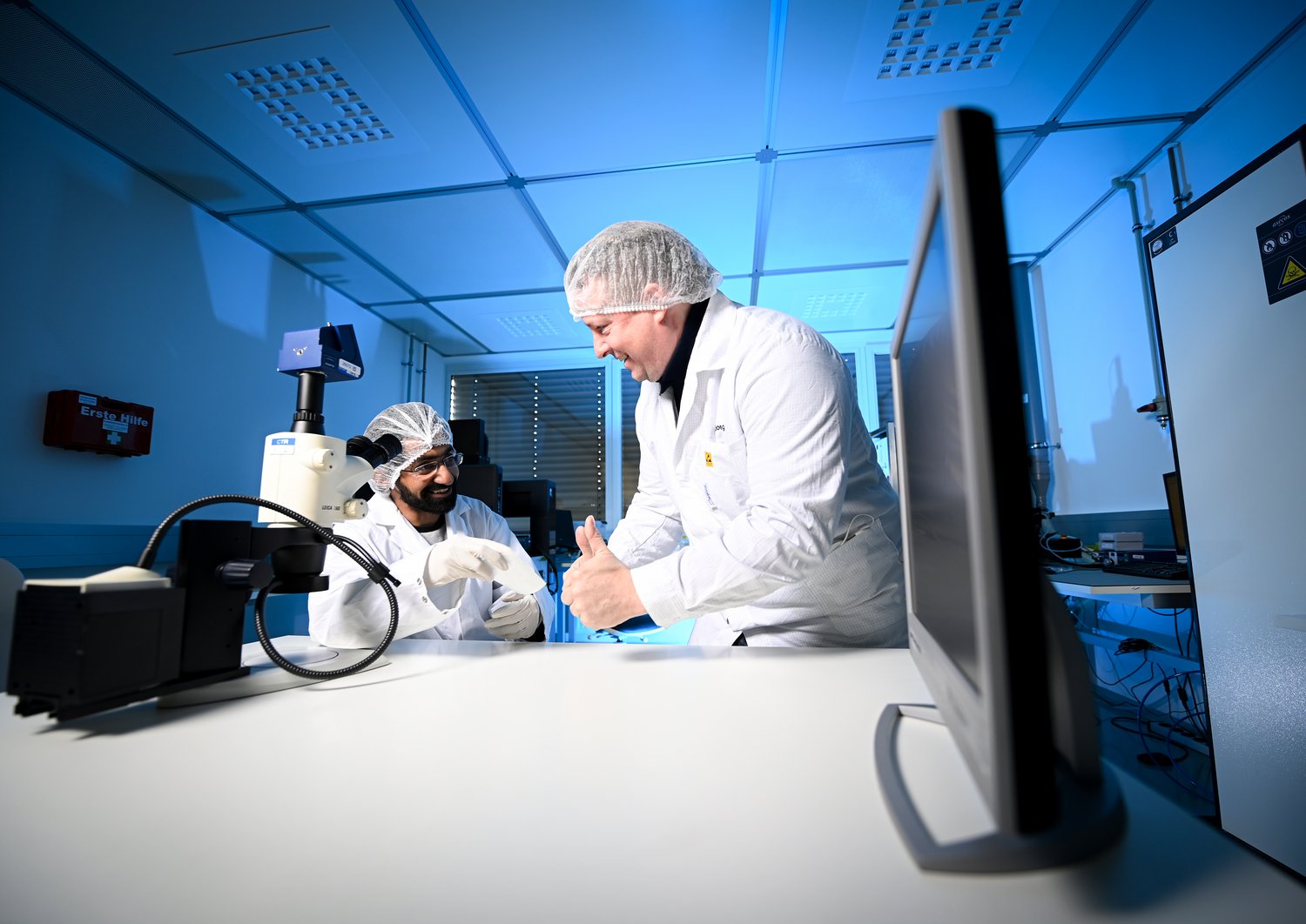 Forscher in Reinraumanzügen im Labor vor einem Messgerät
