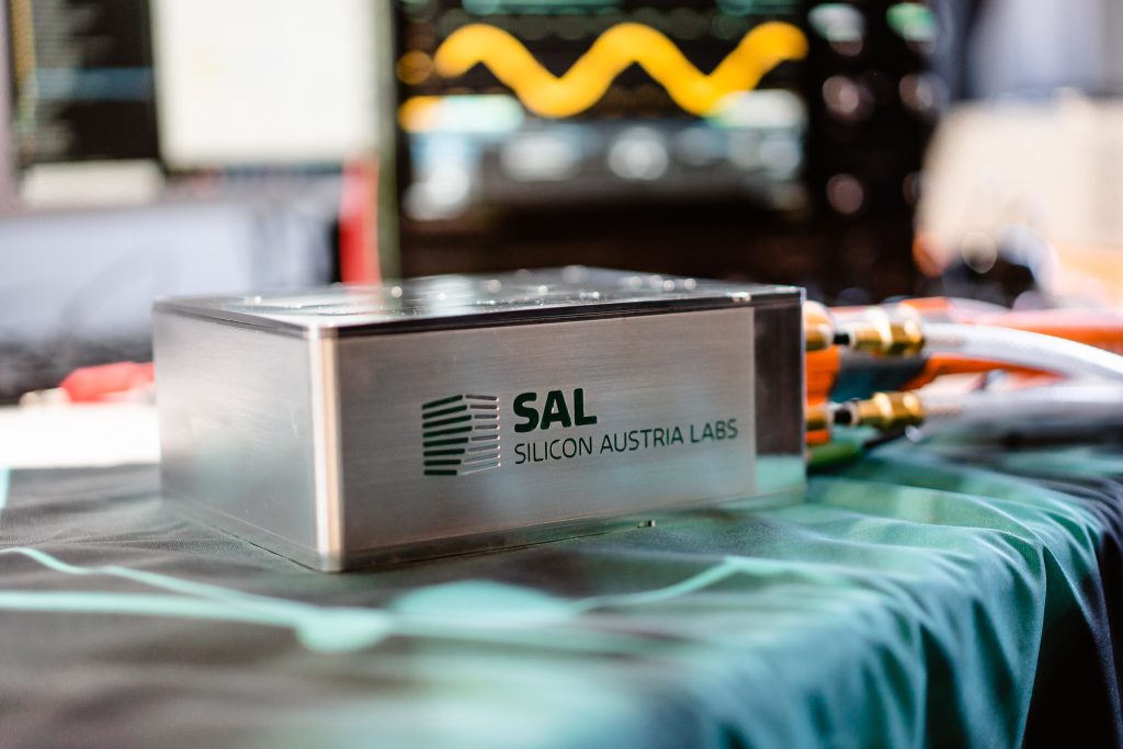 Metallgehäuse der „Tiny Power Box“ von SAL mit angeschlossenen Kabeln auf einem Labortisch.